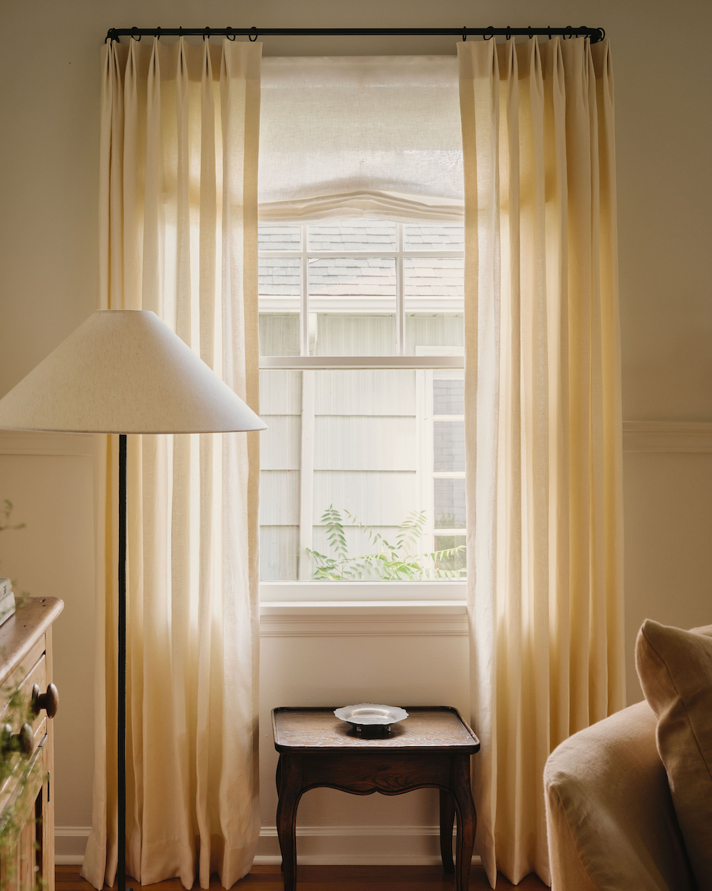 Cafe curtain beneath a window in a green bathroom.