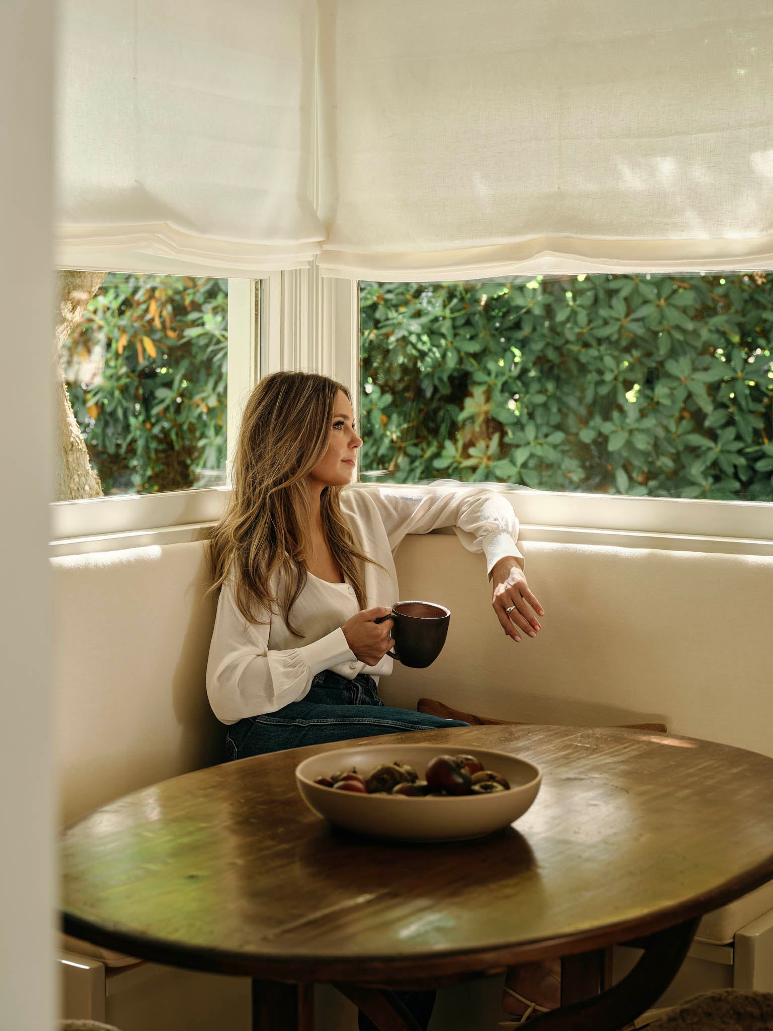 Molly Kidd sitting in a breakfast nook with a cup of coffee.