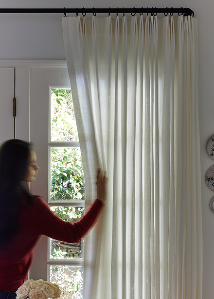 Tailored pleat drapery pulled back from a window.